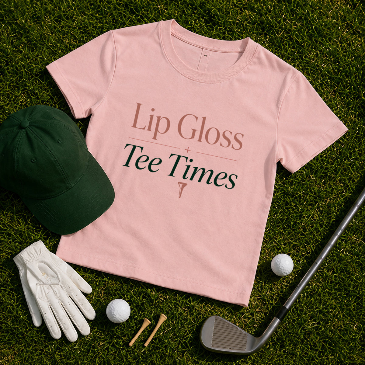 Lip Gloss & Tee Times women's golf tee styled with dark green hat, golf balls, golf tees and golf club