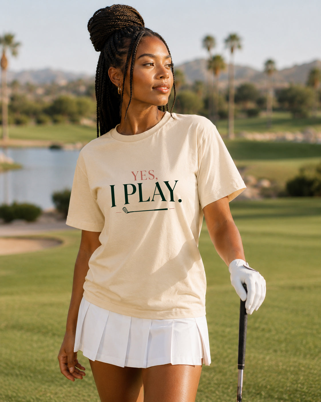 Woman wearing Yes. I Play. women's golf tee with white pleated skirt on golf course